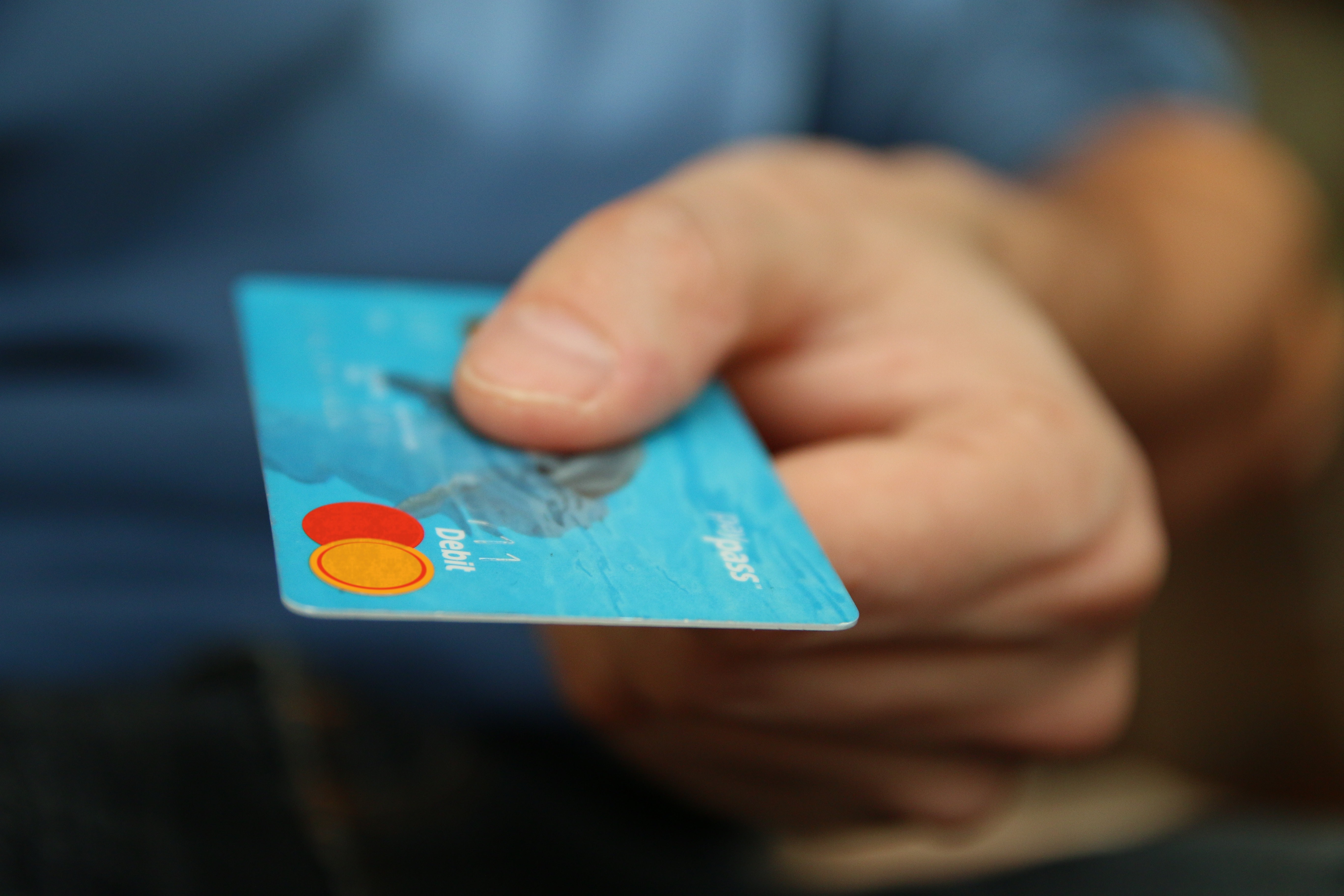 A person handing over a blue debit card. 